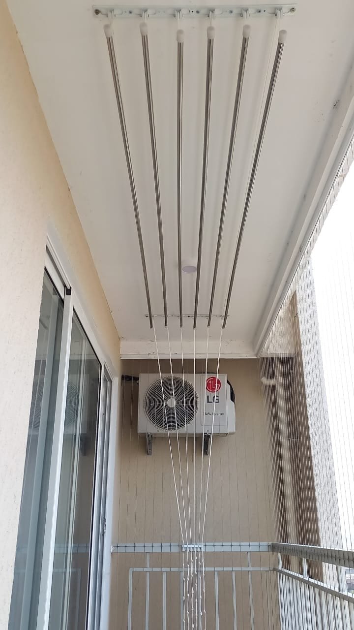 Ceiling cloth hanger installed above an outdoor AC unit on an apartment balcony