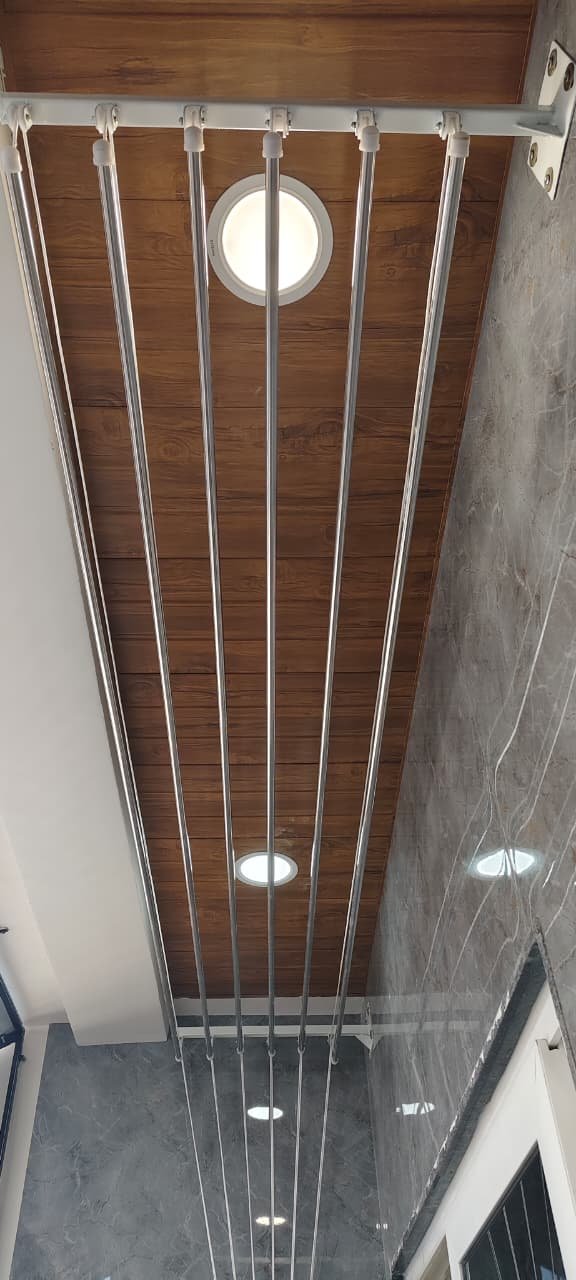 Stainless steel drying rods running under a wooden ceiling beside a round light