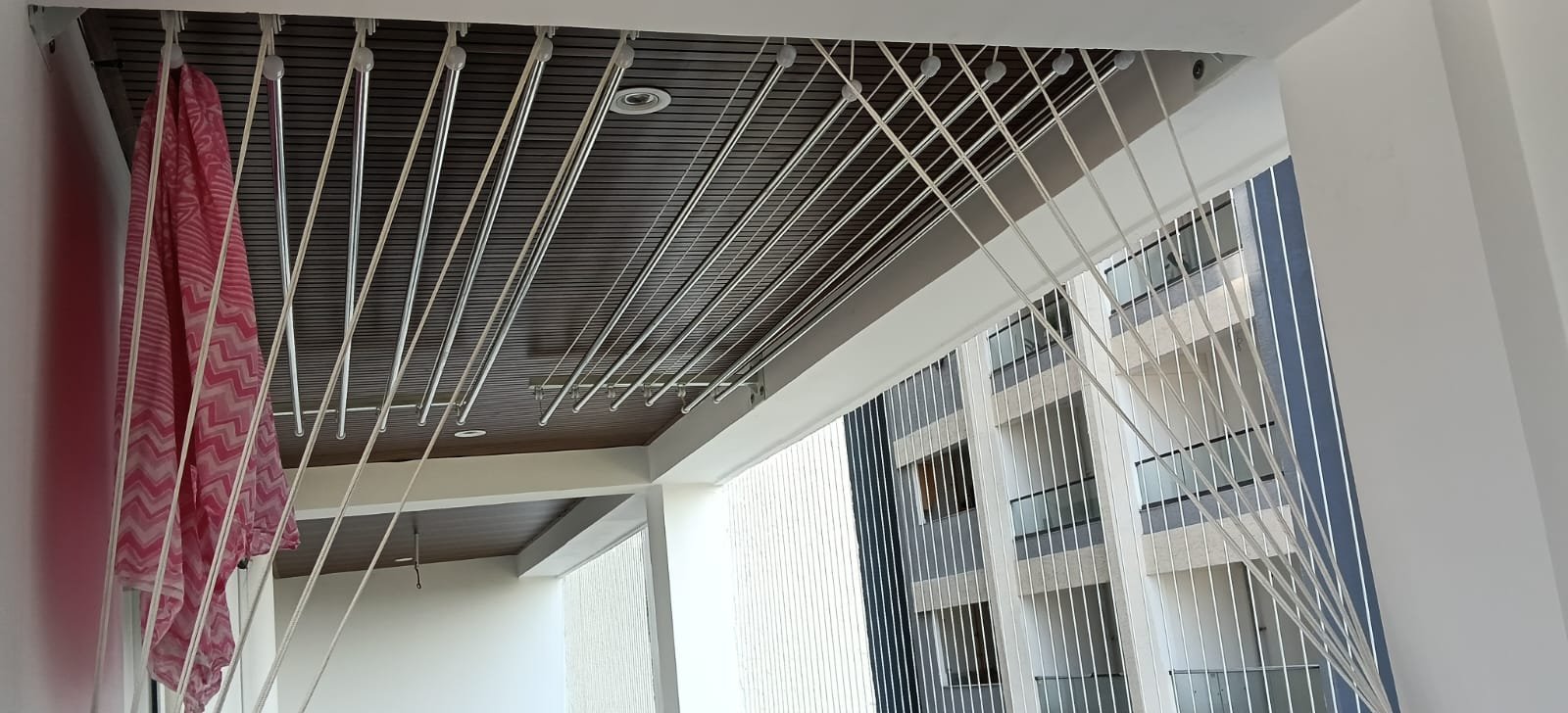 Six-rod ceiling hanger fitted to a dark wooden plank ceiling in a netted balcony
