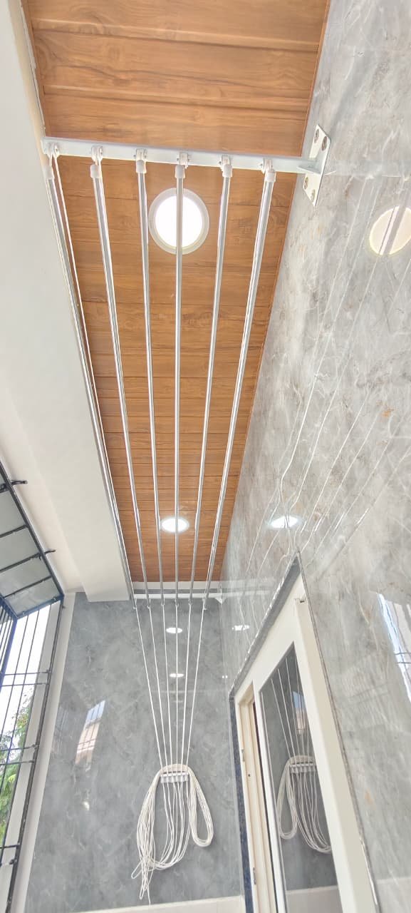 Compact ceiling cloth hanger fitted in a utility area with a teak ceiling