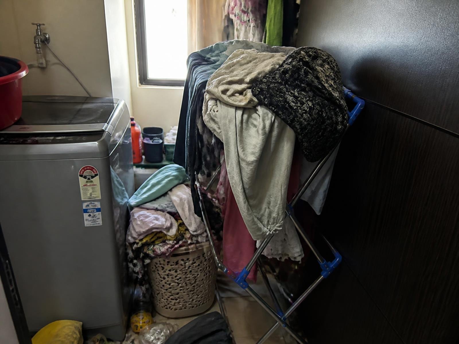 Cramped utility area with laundry piled on a floor stand before installation